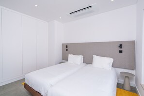 Ein modernes Hotelzimmer mit einem Doppelbett, einem Nachttisch, einem kleinen runden Tisch und einem Kleiderschrank.
