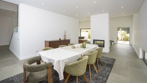 A modern dining area with a long table, chairs, and a fireplace. - Bazaruto T4 swimingpool Lagos (Lagos)