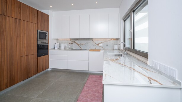 A modern kitchen with wooden cabinets, a built-in oven, white countertops, and a large window. - Bazaruto T4 swimingpool Lagos (Lagos)
