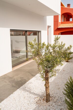 A modern building with a glass door entrance, a small tree in the foreground, and a gravel ground. - Bazaruto T4 swimingpool Lagos (Lagos)
