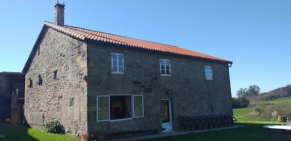 Un bâtiment en pierre avec un toit recouvert de tuiles rouges, une porte et des fenêtres.