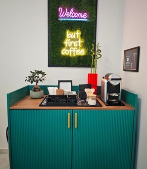 Eine Kaffeestation mit einer Neonreklame, einer Kaffeemaschine und einer kleinen Pflanze.