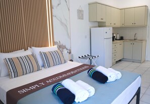 Ein Hotelzimmer mit Bett, einer Frühstückstheke, einem Kühlschrank und einer Küchenzeile.