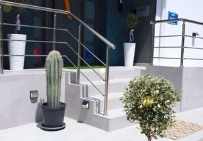 A modern building entrance with a metal staircase, potted plants, and a sign. - Apartment Simply 203 (Skafidaras)