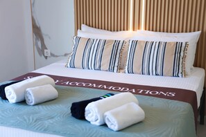 A hotel room with a bed, pillows, and neatly folded towels. - Apartment Simply 203 (Skafidaras)