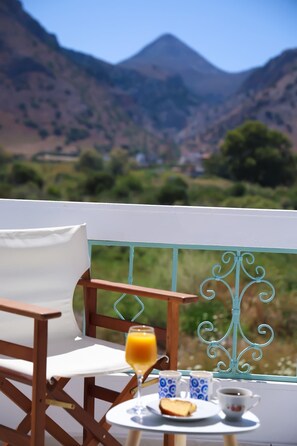 A balcony with a table set for breakfast, a chair, and a view of mountains. - Apartment Simply 203 (Skafidaras)