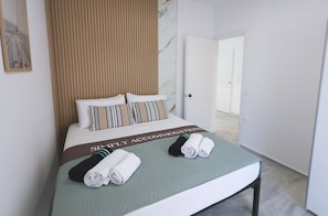 Ein Hotelzimmer mit Bett, Holz-Kopfteil, grüner Bettdecke und einem Schild auf dem Bett.
