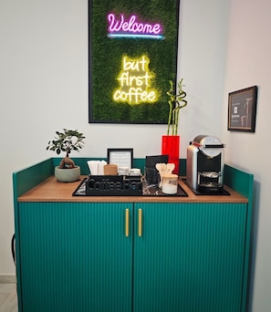 Eine Kaffeestation mit einer Neonreklame, einer Kaffeemaschine und einer kleinen Pflanze.