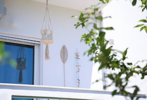 Ein Gebäude mit einer weißen Fassade, einer hängenden Makramee-Lampe und einem Fenster, das die Reflexion einer hängenden Makramee-Lampe zeigt.