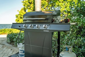 Ein tragbarer Grill mit digitaler Anzeige, vier Bedienelementen und einem Gasbehälter.