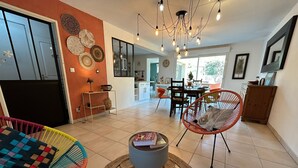 A modern living room with a dining area, a kitchen in the background, and a large window. - Villa Nectar ~ Garden ~ Parking ~ Air Conditioning (Beauzelle)