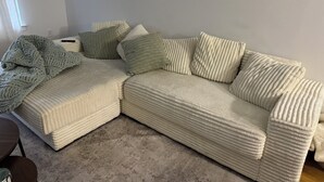 Un sofà modular amb teixit amb textura, una manta i diversos coixins.