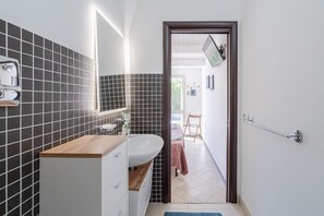 Een moderne badkamer met een houten wastafel, een witte wasbak en een spiegel.