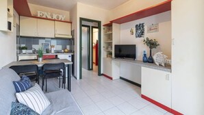 Un espacio habitable compacto con kitchenette, comedor y zona de estar.