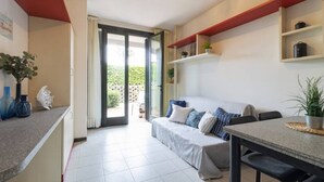 Una cocina moderna con comedor, sofá y vistas a un jardín a través de un ventanal.
