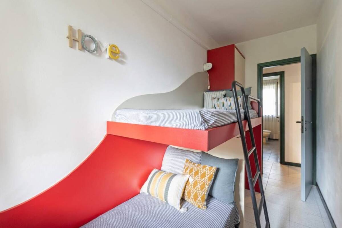 A bunk bed with a red and white color scheme, a ladder, and a 'home' sign on the wall.
