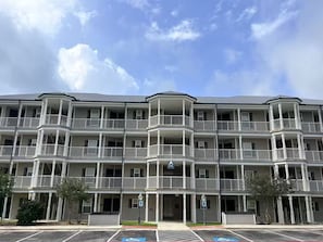 A multi-story building with balconies, a parking lot, and a clear sky. - 2-bedroom condo in Canyon Lake with AC Unit 418 (Canyon Lake)