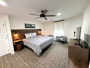 A hotel room with a bed, a desk, a chair, a ceiling fan, and a TV. - Relaxing 2-Bedroom Condo with AC, WiFi in Scenic Canyon Lake (Canyon Lake)