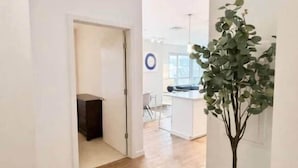 Un interior moderno con suelo de madera, una planta en maceta y una zona de cocina al fondo.