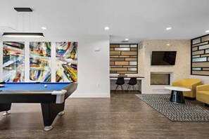 Uma sala de estar moderna com mesa de bilhar, arte abstrata, lareira e área de jantar.