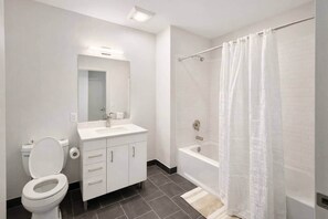 Un baño con inodoro, lavamanos, espejo y ducha.