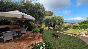 An outdoor patio with wicker furniture, a large umbrella, and potted plants. - VILLA MATILDA IN ANSEDONIA (Toscana)