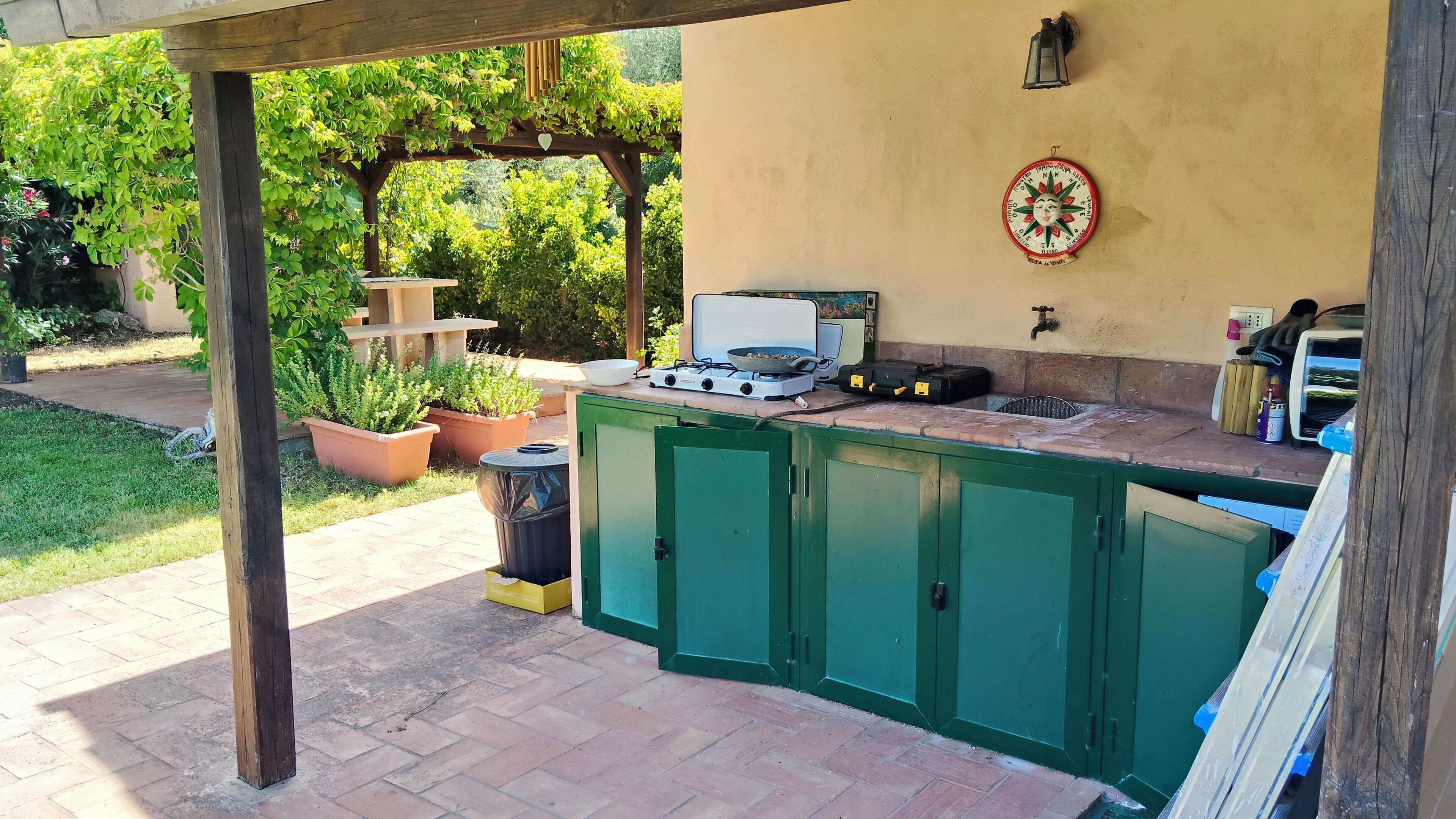 An outdoor kitchen area with a gas stove, a sink, and potted plants.