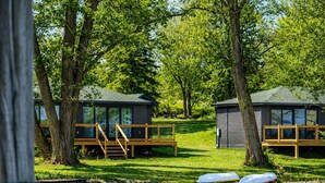 Una baia con un cottage, una veranda, un piccolo molo e un’area verde.