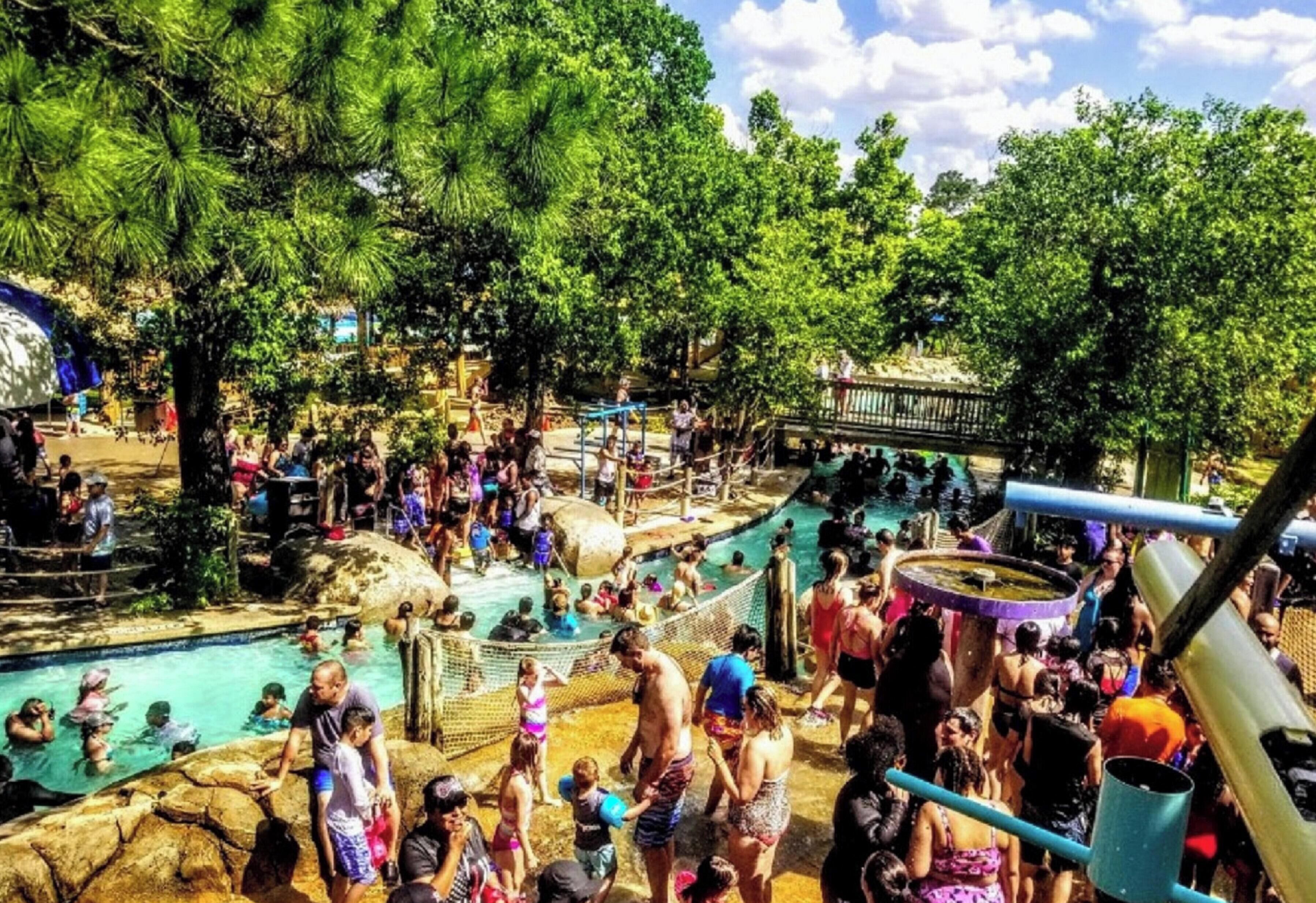 Ein überfüllter Wasserpark im Freien mit mehreren Pools und Wasserrutschen.
