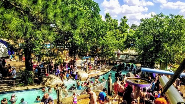 Un grand parc aquatique en plein air, très fréquenté, avec plusieurs piscines et toboggans.