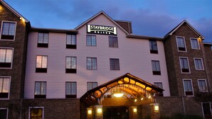 A Staybridge Suites hotel with a brick facade, multiple windows, and a covered entrance.