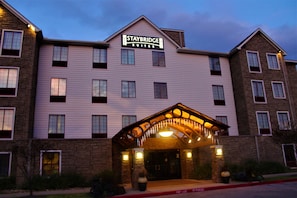 Un hotel Staybridge Suites con fachada de ladrillo, múltiples ventanas y un acceso cubierto.