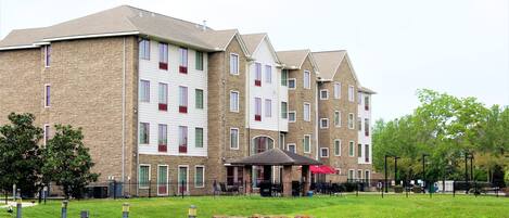 Property building surrounded by lush greenery and open spaces.