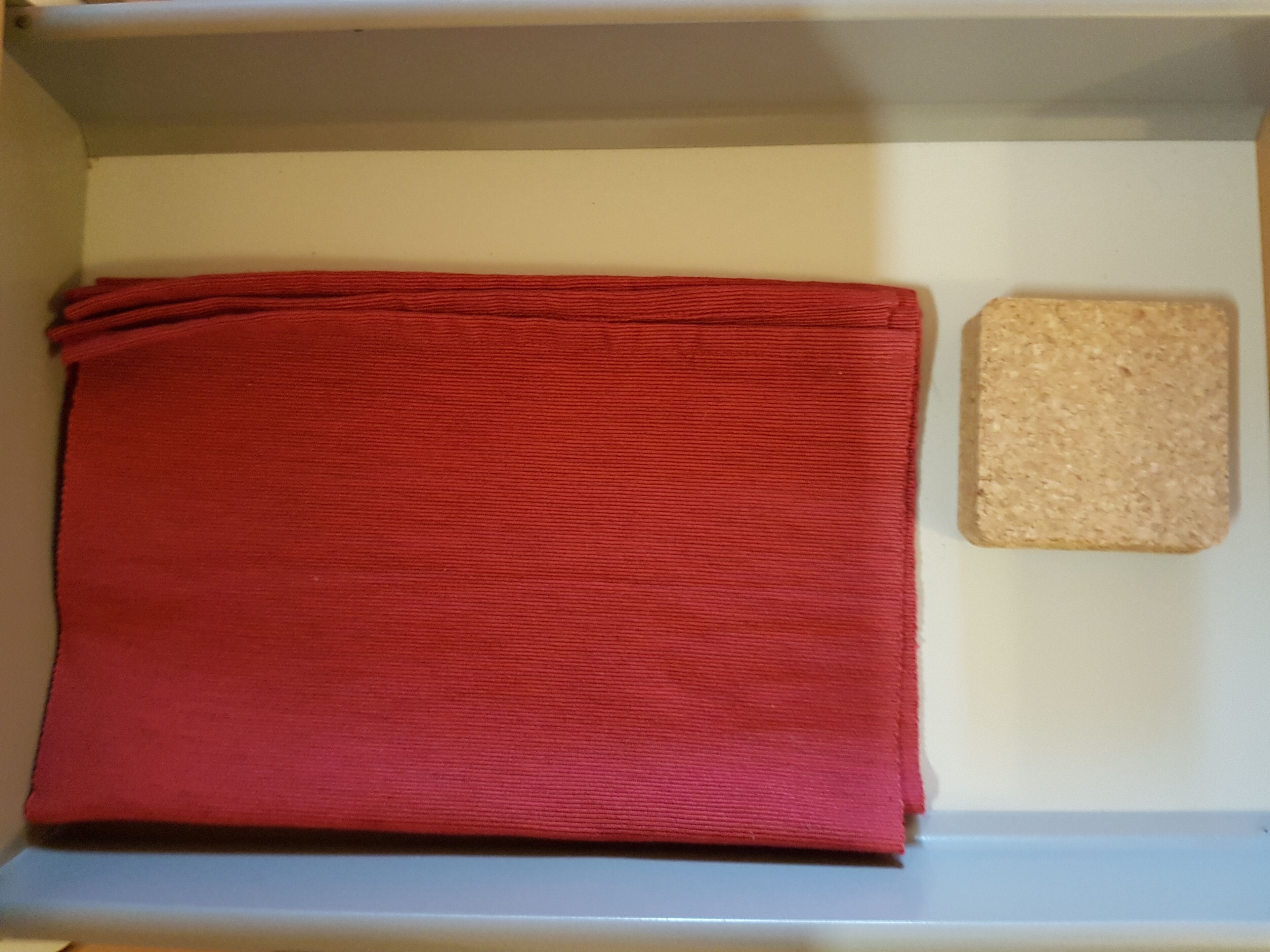 A red fabric item on a shelf, a corkboard, and a white wall.