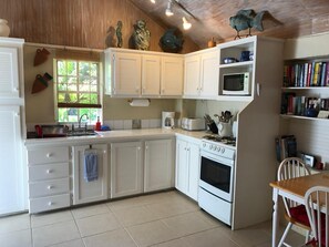 A kitchen with white cabinets, a stove, microwave, and a dining area with a table and chairs.