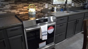Una cocina con horno de acero inoxidable, hervidor y una toalla colgada en la puerta del horno.