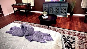 Una habitación con cama, sofá, televisión, armario y una mesita.