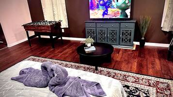 Una habitación con cama, sofá, televisión, armario y una mesita.