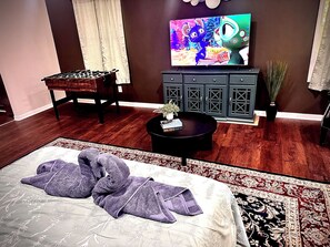 Una habitación con cama, sofá, televisión, armario y una mesita.