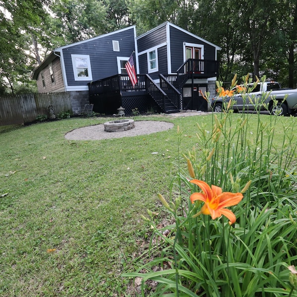 A two-story building with a front porch, a small garden with flowers, and a staircase leading to the entrance.