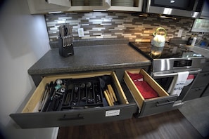 A kitchen with a drawer organizer for utensils, a kettle, and a microwave.