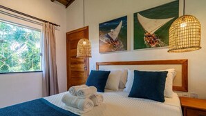 Una cama bien hecha con toallas enrolladas, un cabecero de madera y cuadros en la pared.
