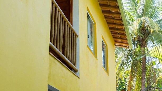 Un edificio amarillo con balcón y ventanas de madera.