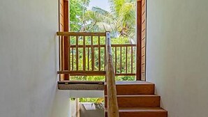 Una escalera de madera con barandilla que lleva a un balcón con vistas al verdor.