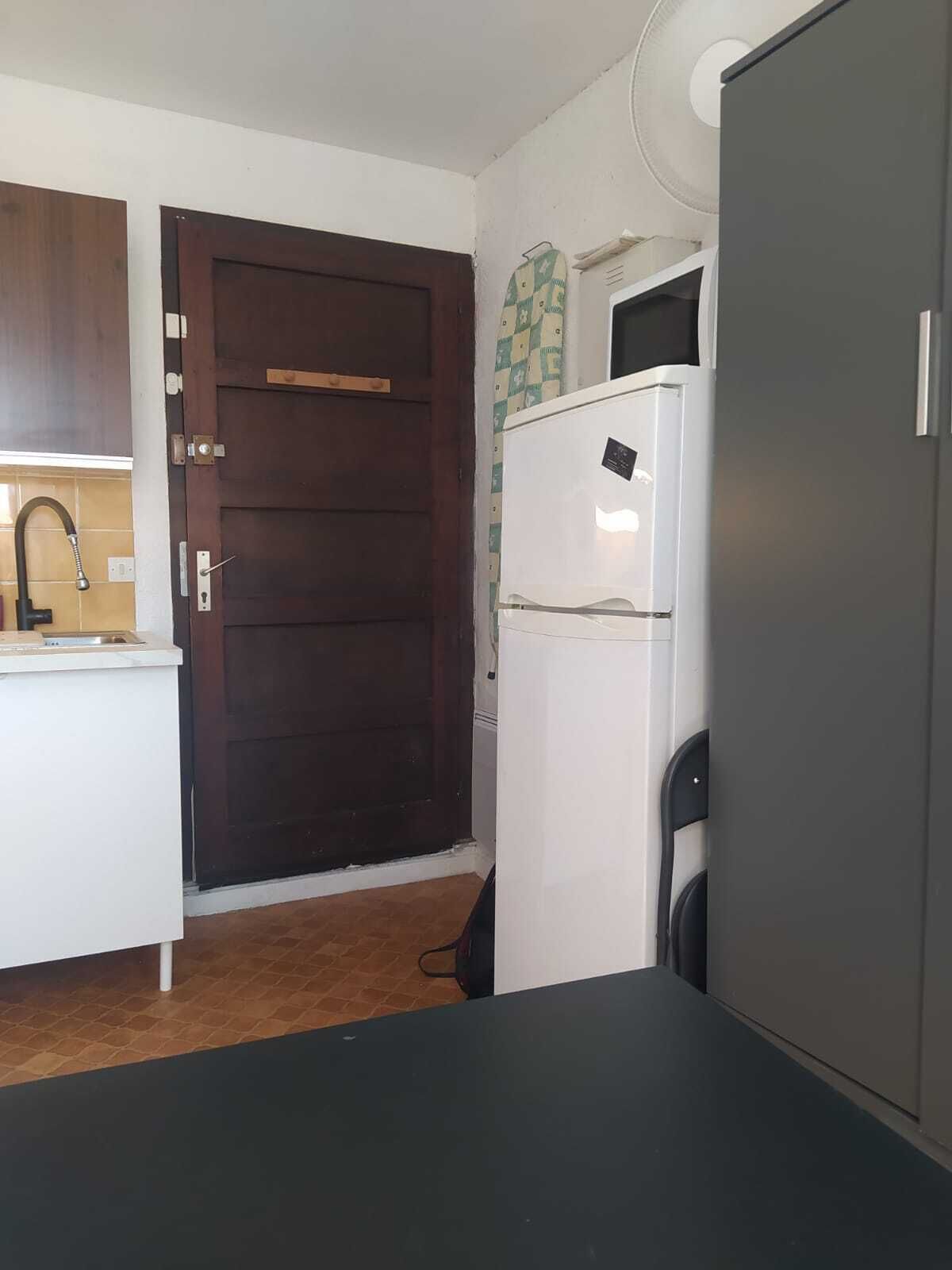 A kitchen with a dark wooden door, a white refrigerator, and a tiled backsplash.