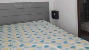 A bedroom with a bed, a wall-mounted picture, a headboard with text, and a door. - Studio apartment in a residential complex on the edge of a pond (Le Barcarès)