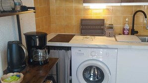 A compact kitchen with a washing machine, coffee maker, and a small countertop with a kettle. - Studio apartment in a residential complex on the edge of a pond (Le Barcarès)