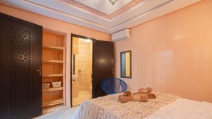 A bedroom with a bed, a wardrobe, a bathroom, and a mirror. - Riad 3ch Salon, Terrasse avec Jacuzzi ,à Jemaa El Fna (Marrakech)