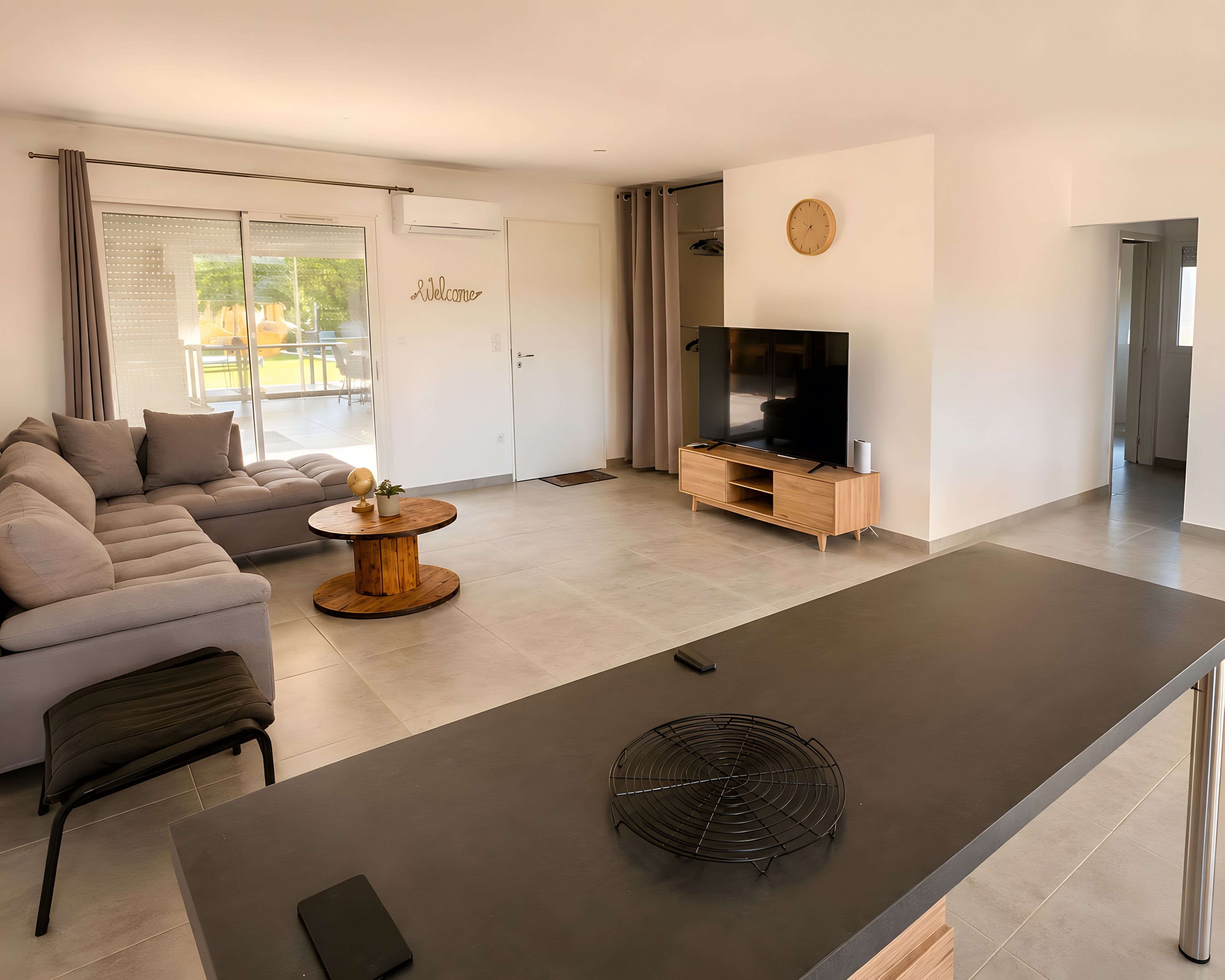 En moderne stue med sofa, sofabord, fjernsyn og spiseplads.