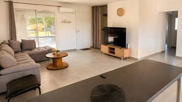 En moderne stue med sofa, sofabord, fjernsyn og spiseplads.